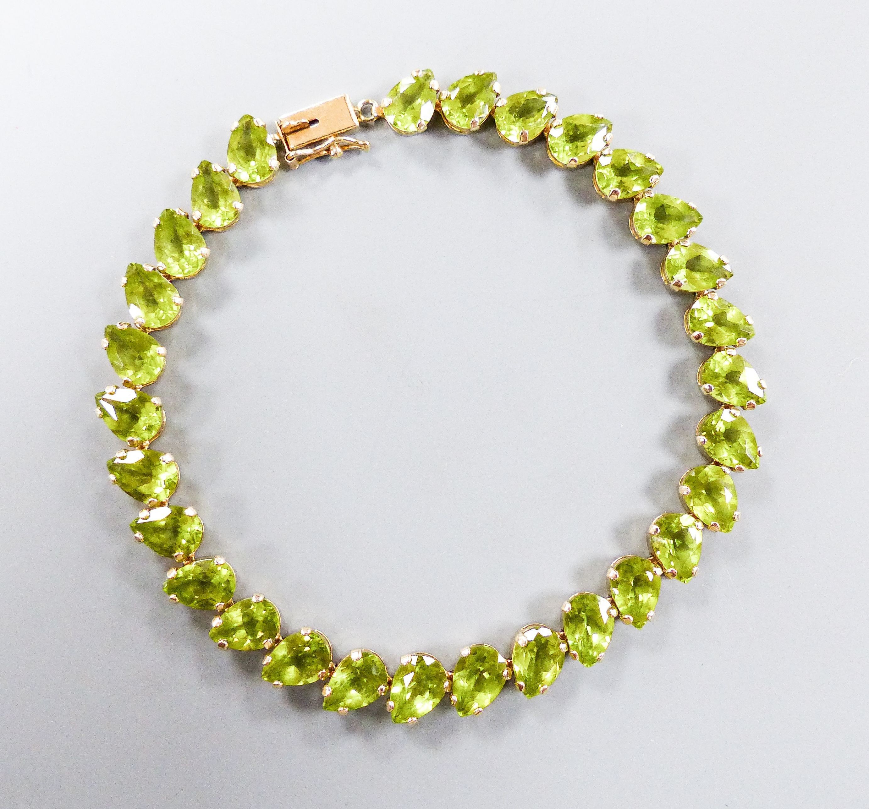 A modern 10k and pear cut peridot set line bracelet, 19cm, gross weight 9.4 grams.